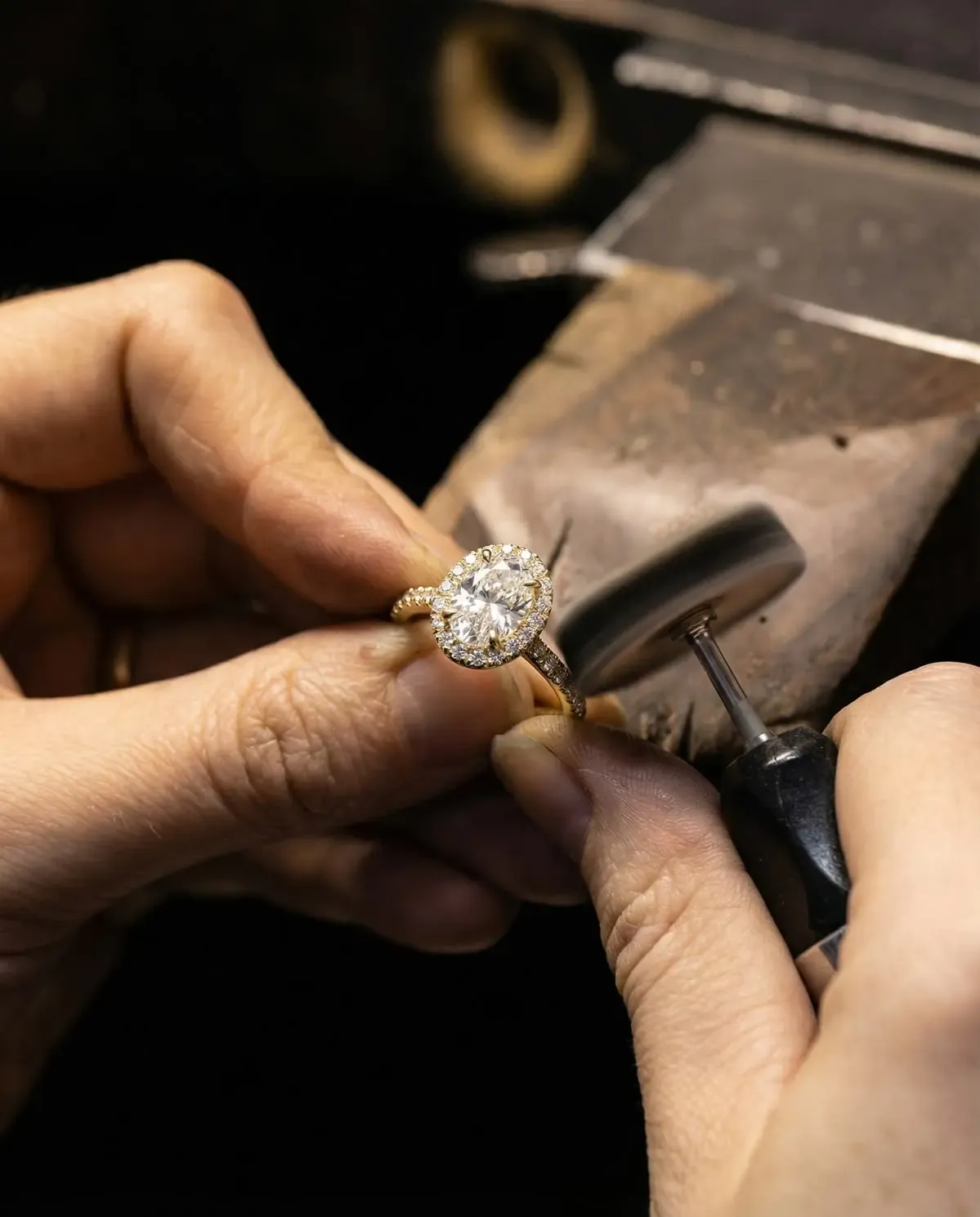 A jeweller polishing a diamond halo ring at the bench